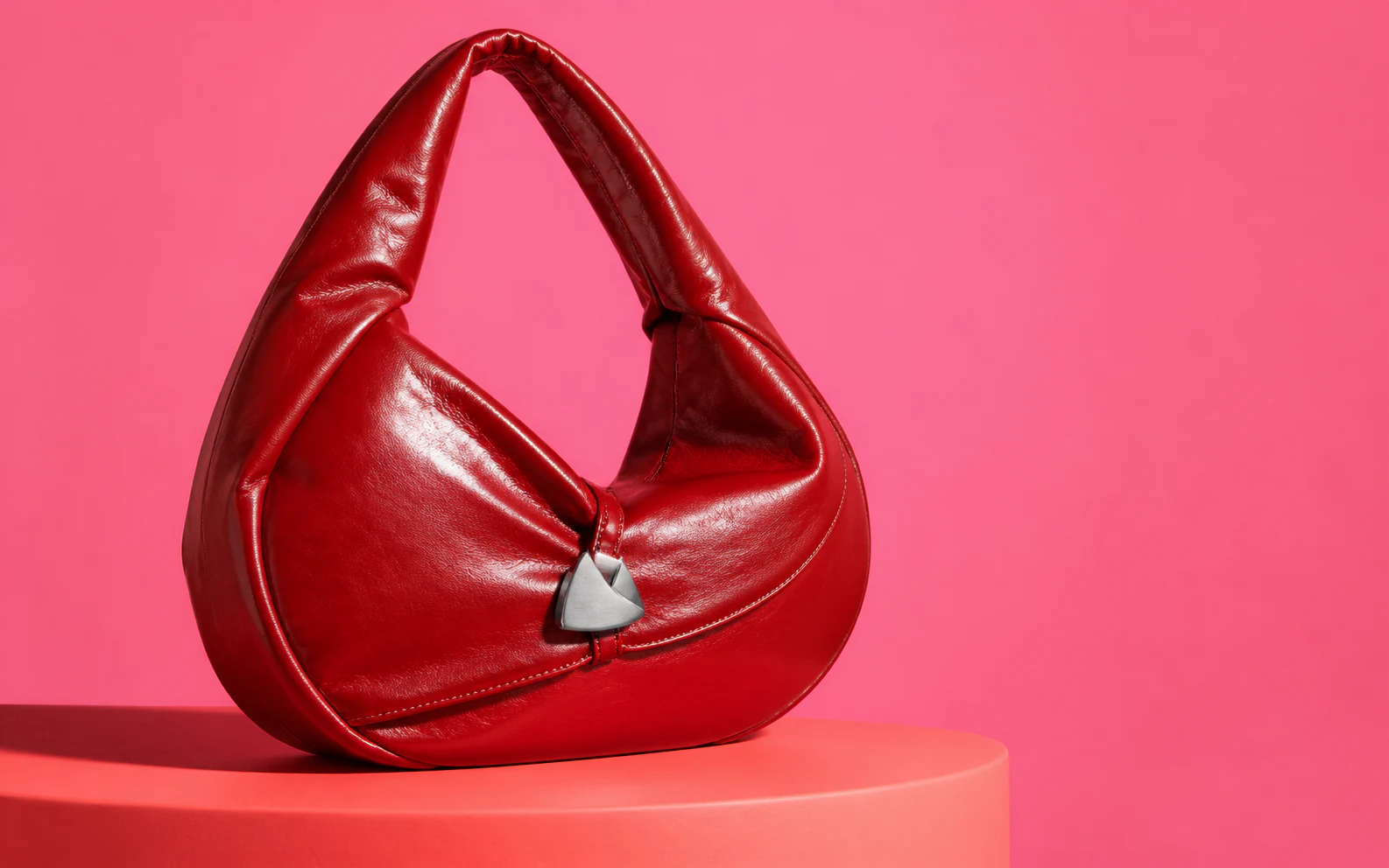 Sculptural cherry-red leather shoulder bag on a pink studio set
